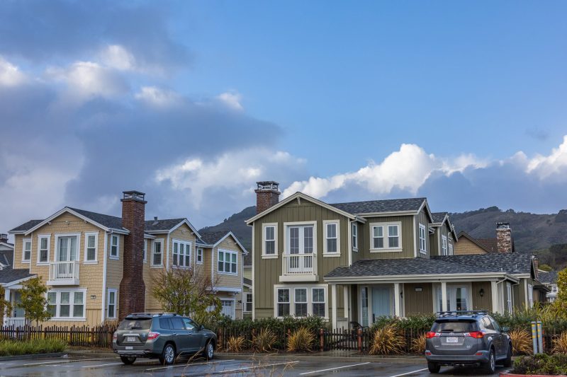 Picturesque suburban neighborhood with modern houses and parked cars under a partly cloudy sky